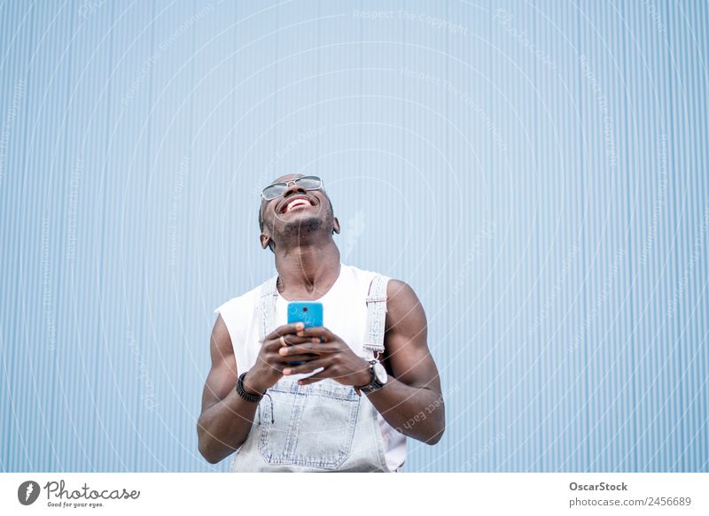 African man blue background with mobile phone. Lifestyle Style Happy To talk Telephone Technology Human being Man Adults Fashion Afro Old To enjoy Listening