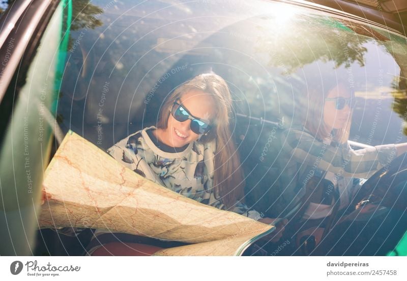Happy young woman looking a map inside of car Lifestyle Joy Beautiful Leisure and hobbies Vacation & Travel Trip Human being Woman Adults Friendship Couple