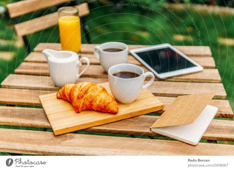 Morning Breakfast In Green Garden With French Croissant, Coffee Cup, Orange Juice, Tablet and Notes Book On Wooden Table Background picture Summer White Food