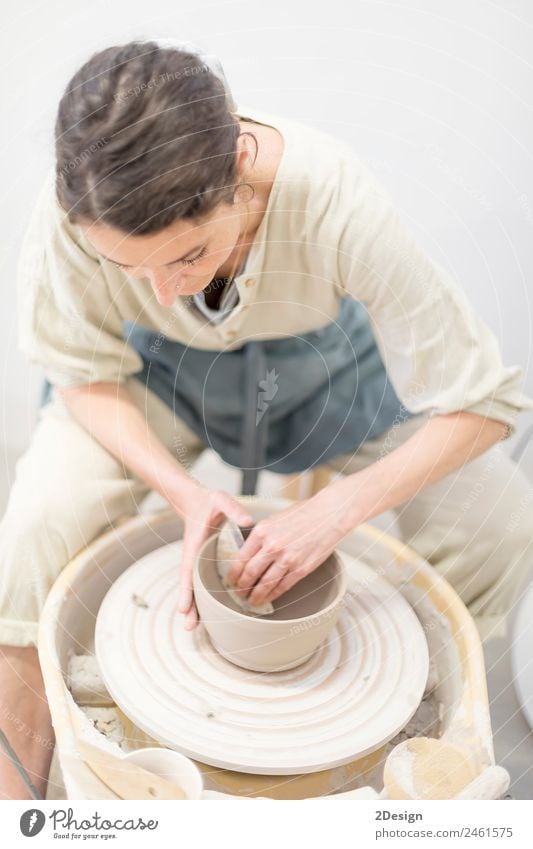 Young female sitting by table and making clay or ceramic mug Crockery Leisure and hobbies Handcrafts Table Work and employment Profession Craftsperson Workplace
