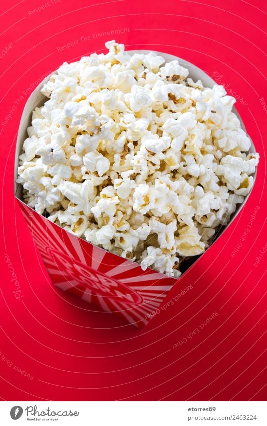 Striped box with popcorn on red background. Food Nutrition Eating Organic produce Finger food Red Popcorn Cinema Salt Butter Snack White Delicious Maize