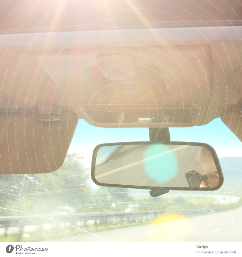 Sunny car ride. View through the windshield onto the highway. Eyes and glasses of the driver as reflection in the rear view mirror. Vacation & Travel Summer 1