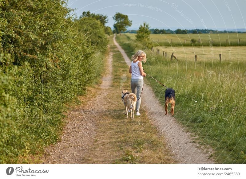 Young blond woman walking her two dogs Lifestyle Happy Beautiful Summer Woman Adults Friendship 1 Human being Nature Animal Warmth Grass Park Blonde Pet Dog