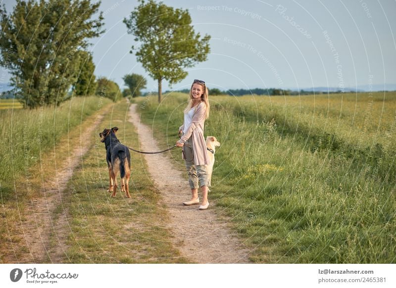 Attractive smiling blond woman with her two dogs Lifestyle Happy Beautiful Summer Woman Adults Friendship Nature Animal Warmth Grass Park Blonde Pet Dog Smiling
