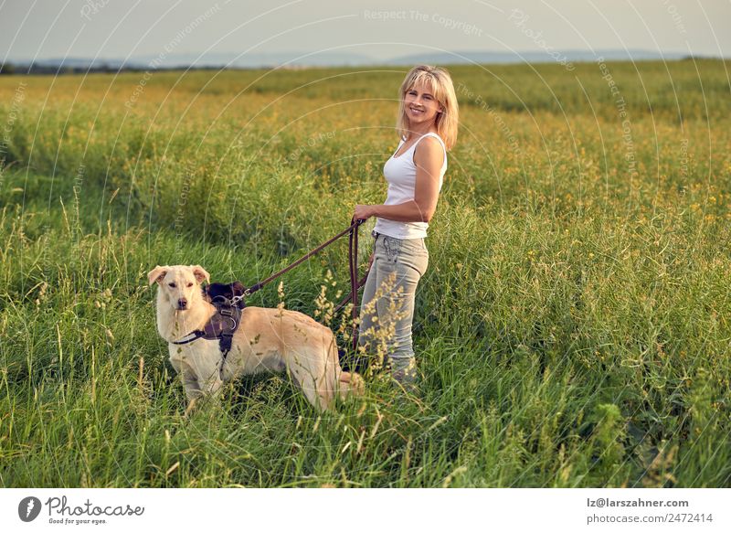 Blond woman walking her dogs at sunset Lifestyle Beautiful Summer Woman Adults Friendship 1 Human being 45 - 60 years Nature Landscape Animal Warmth Grass