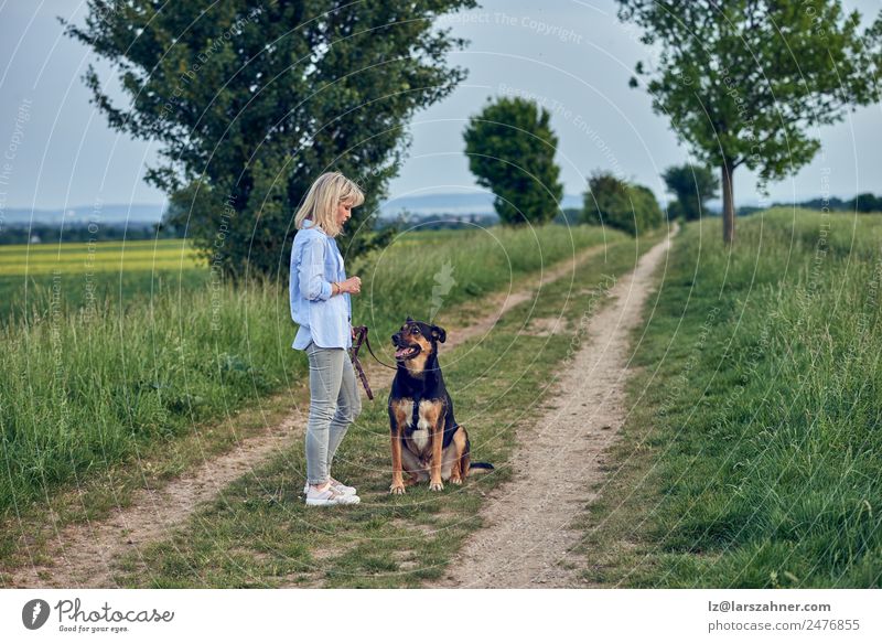 Attractive young woman teaching her dog Summer Woman Adults Friendship 1 Human being 45 - 60 years Landscape Animal Lanes & trails Blonde Dog Stand Rural