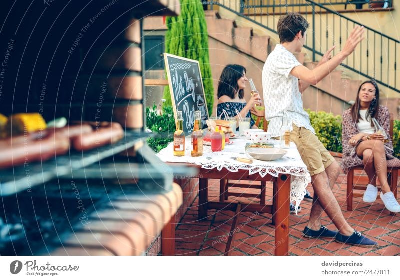 Young people talking outdoors and meal cooking in furnace Sausage Lunch Alcoholic drinks Beer Lifestyle Joy Happy Relaxation Leisure and hobbies Summer Garden