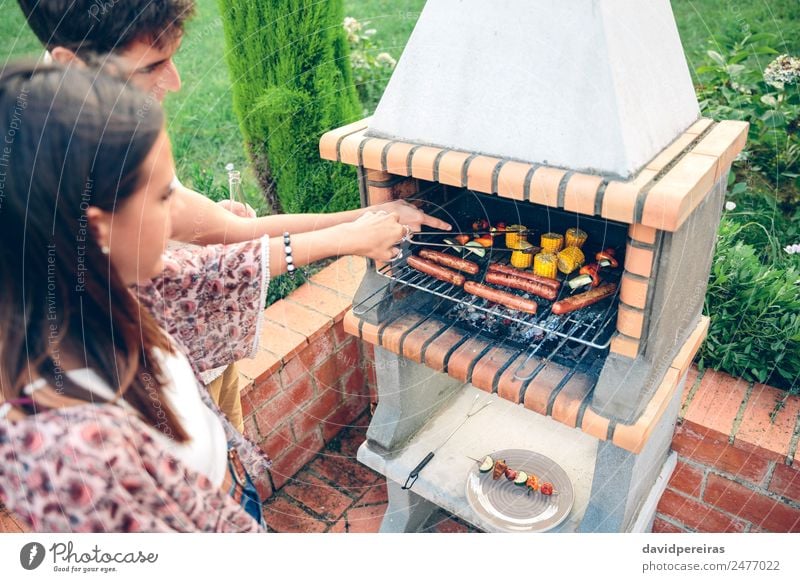 Friends cooking in barbecue on summer party Sausage Vegetable Lifestyle Joy Happy Relaxation Leisure and hobbies Summer Garden Woman Adults Man Friendship Hand