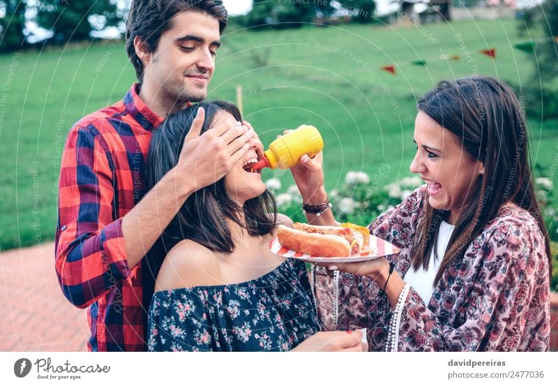 Man holding hot dog in barbecue with friends Sausage Eating Fast food Plate Lifestyle Joy Happy Summer Woman Adults Friendship Mouth Hand To enjoy Smiling