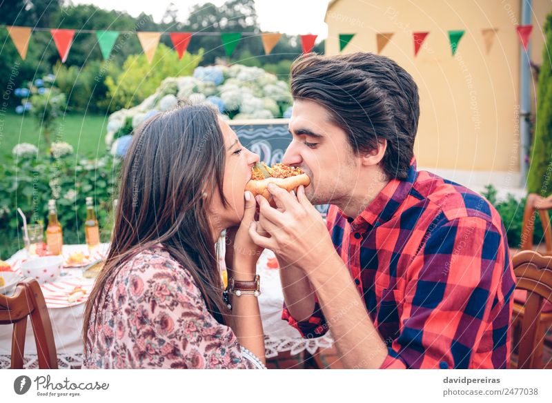 Funny young couple eating an american hot dog Sausage Bread Roll Lunch Fast food Lifestyle Joy Happy Summer Woman Adults Man Friendship Couple Hand Dog To enjoy