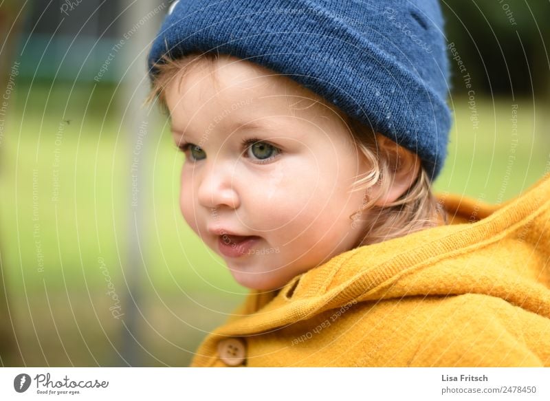 Toddler with cap Parenting Child Girl 1 Human being 1 - 3 years Cap Observe Looking Natural Blue Yellow Contentment Leisure and hobbies Infancy Concentrate