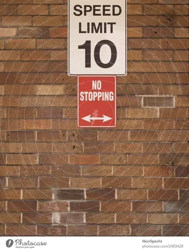 going slow Wall (barrier) Wall (building) Stone Characters Signs and labeling Signage Warning sign Town Brown Red White Speed limit No standing Brick wall