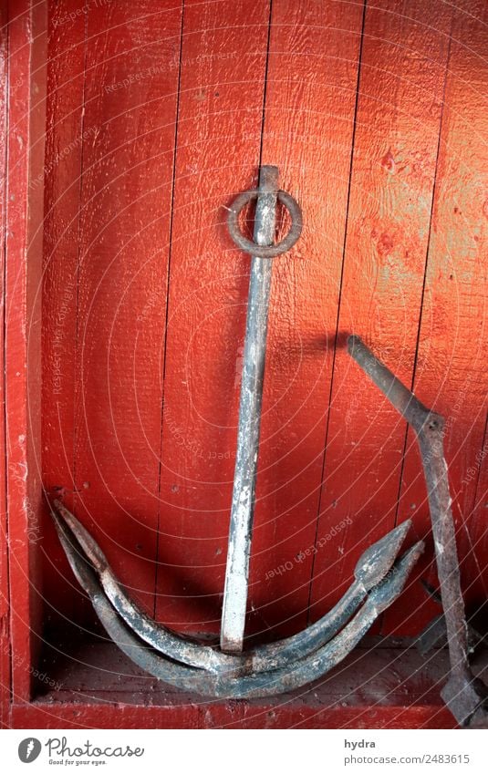 Old anchor Stockanke in front of red wooden wall in boat shed - a