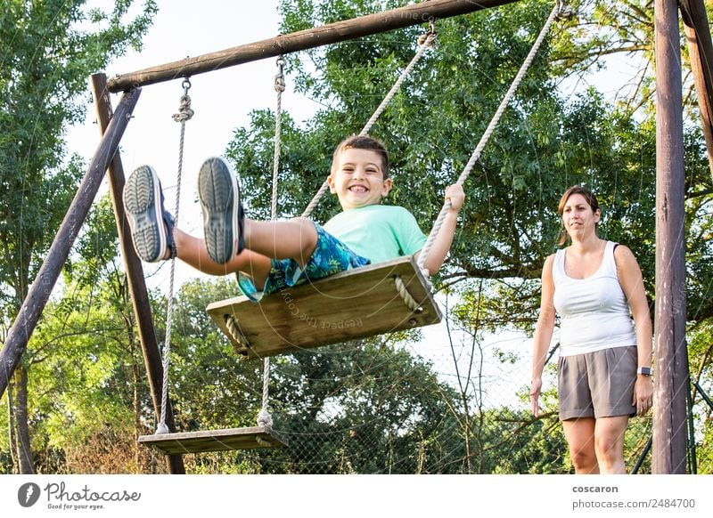 Mother swinging her son on a swing Lifestyle Joy Happy Beautiful Relaxation Leisure and hobbies Playing Child Human being Boy (child) Woman Adults Man Parents
