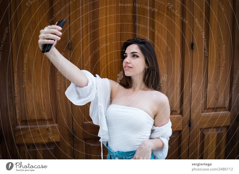 Smiling woman taking selfie at wooden door Elegant Style Happy Beautiful Calm Leisure and hobbies Summer PDA Technology Woman Adults Clothing Brunette Wood