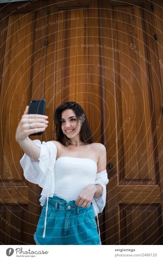 Cheerful young woman taking selfie on smartphone Style Happy Beautiful Calm Leisure and hobbies Summer PDA Technology Woman Adults Clothing Brunette Wood