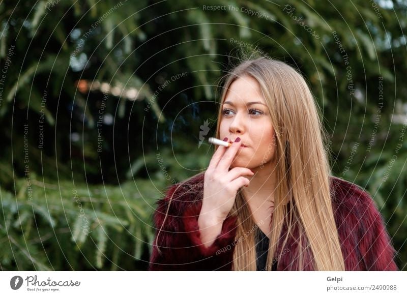 Pretty blond girl with long hair smoking Lifestyle Elegant Style Joy Happy Beautiful Face Make-up Human being Woman Adults Nature Grass Park Fashion Fur coat