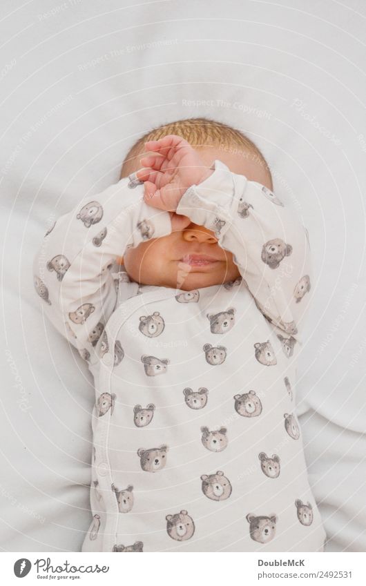 Baby lies on a blanket and covers his eyes with his hands Human being Body Head by hand Fingers 1 0 - 12 months Lie Uniqueness Small Soft Brown Orange Pink