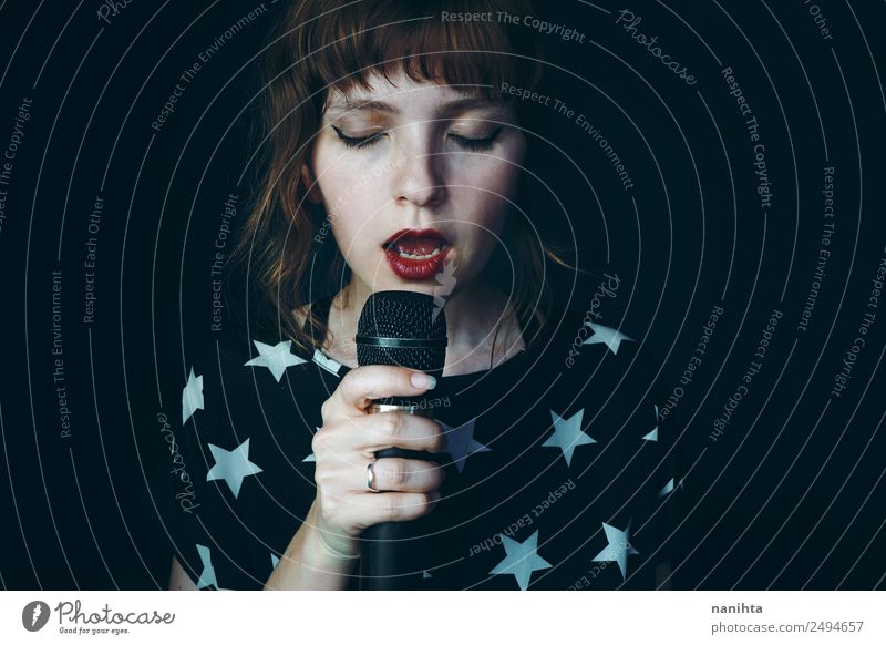 Young woman singing into the darkness Lifestyle Elegant Style Design Face Leisure and hobbies Party Event Music Feasts & Celebrations Technology Microphone