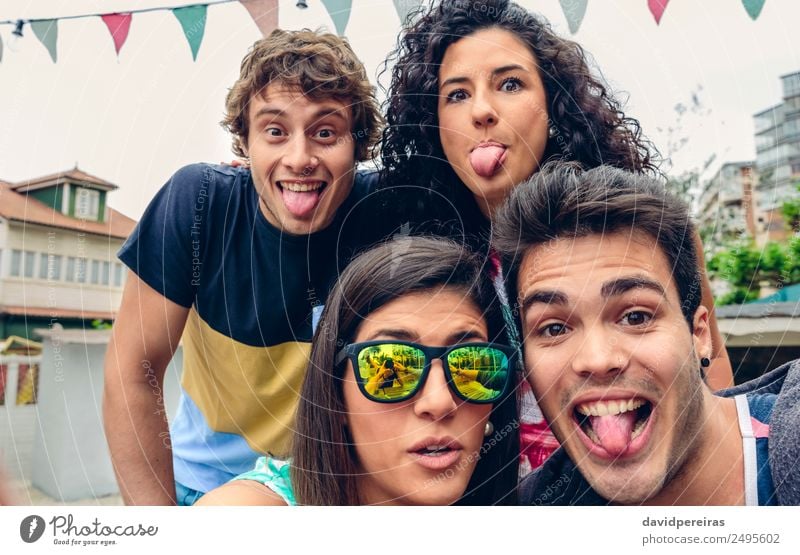 Close up of young happy people looking at camera and sticking out tongues fun in a summer party outdoors Lifestyle Joy Happy Leisure and hobbies