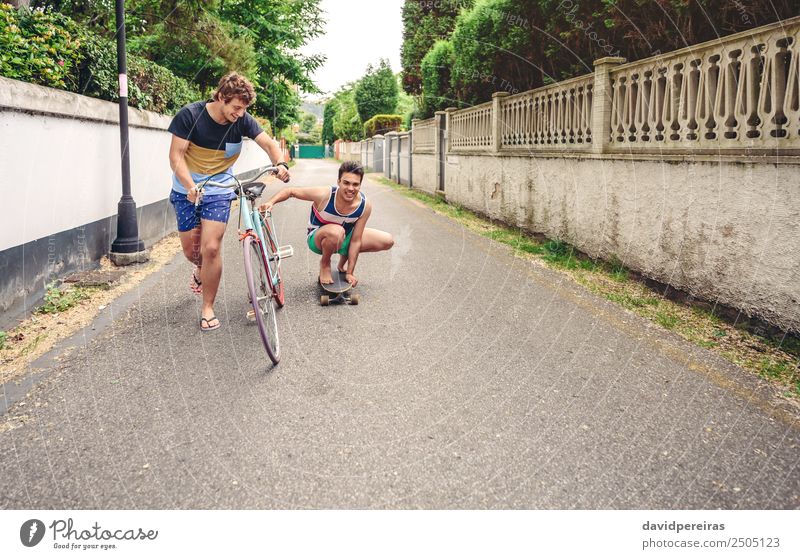Two men having fun riding bike and skateboard Lifestyle Joy Happy Relaxation Leisure and hobbies Vacation & Travel Summer Sports Man Adults Friendship