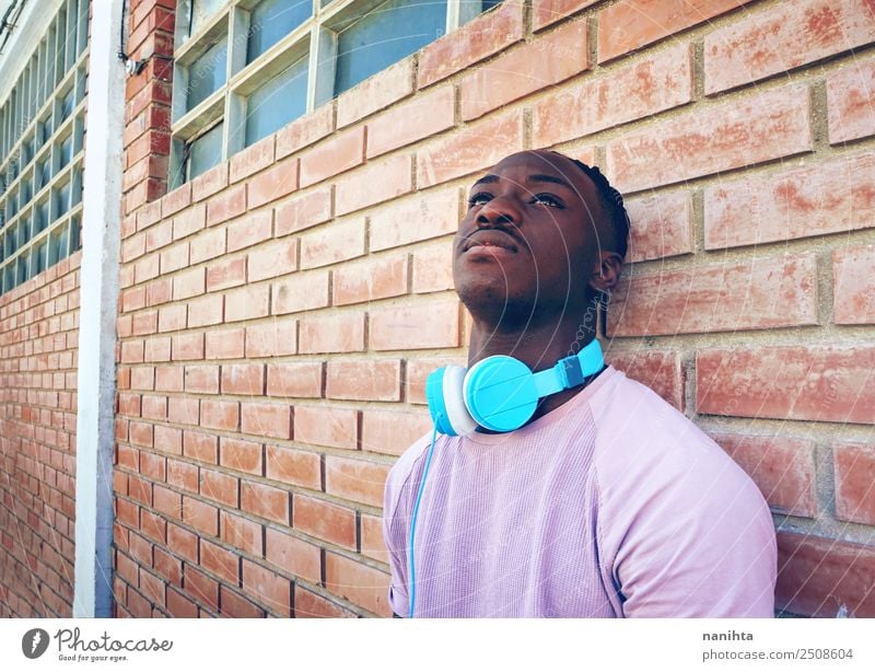 Young black man against a brick wall Lifestyle Style Design Senses Relaxation Leisure and hobbies Headset Headphones Technology Entertainment electronics