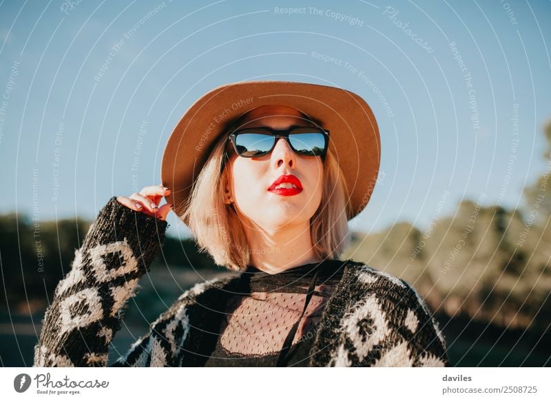 Portrait of blonde woman with hat, sunglasses and red lips enjoying nature at sunset. Lifestyle Luxury Elegant Style Beautiful Sun Human being Feminine
