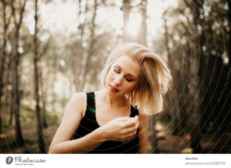 White blonde woman touching her hair in the middle of the forest with the sun in the background. Lifestyle Style Hair and hairstyles Wellness Human being
