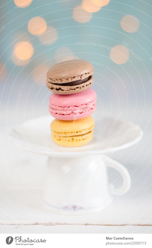 Three colorful macarons on a plate. Food Dough Baked goods Candy Breakfast To have a coffee Crockery Glass Elegant Decoration Lamp Table Eating Feeding Blue