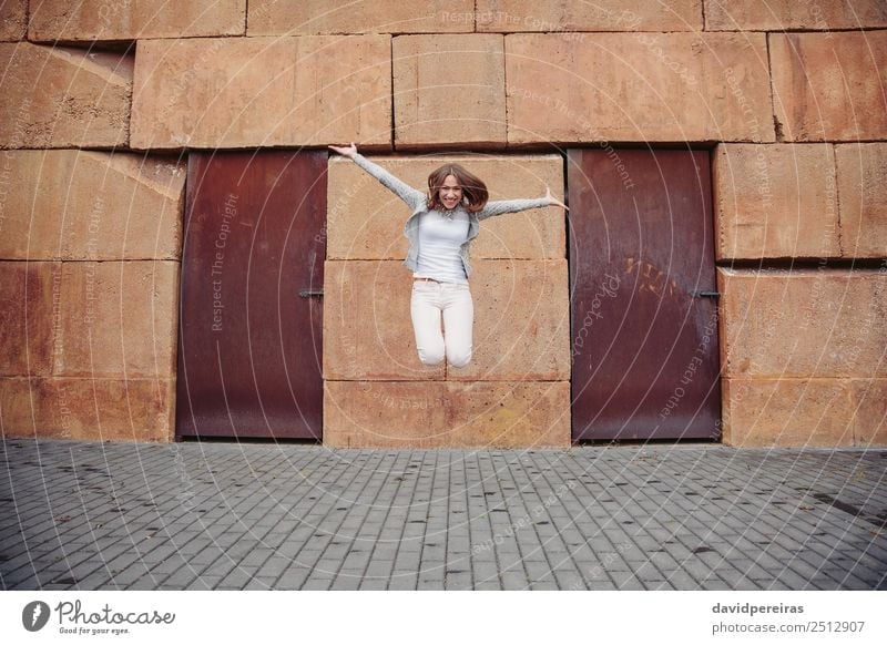 Happy woman jumping in front of stone wall background Lifestyle Joy Beautiful Leisure and hobbies Freedom Human being Woman Adults Street Fashion Clothing Jeans