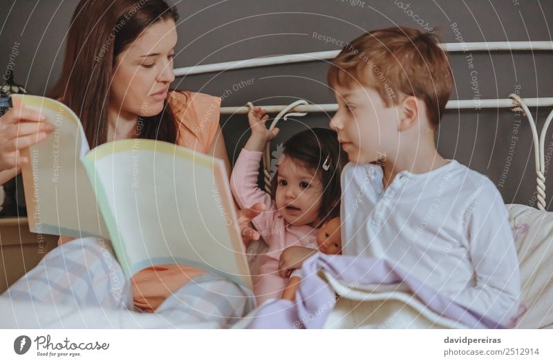 Mother reading book to her sons in the bed Lifestyle Joy Happy Beautiful Relaxation Leisure and hobbies Reading House (Residential Structure) Bedroom Child Baby