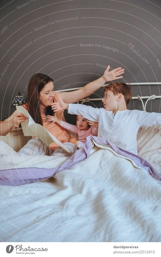 Mother reading book to her sons in the bed Lifestyle Joy Happy Beautiful Relaxation Leisure and hobbies Reading House (Residential Structure) Bedroom Child Baby