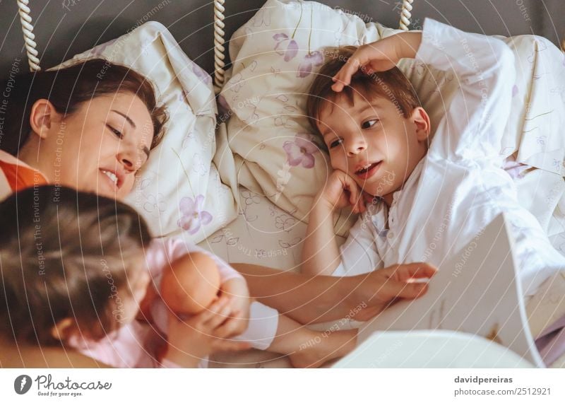 Mother reading book to her sons in the bed Lifestyle Joy Happy Beautiful Relaxation Leisure and hobbies Reading Bedroom Child Baby Boy (child) Woman Adults