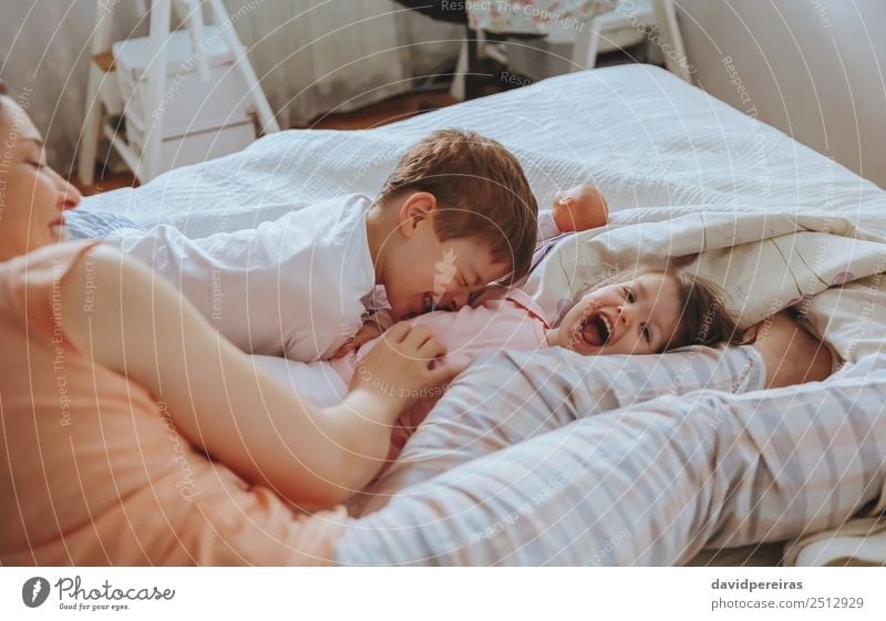 Happy family playing over bed in morning Lifestyle Joy Beautiful Relaxation Leisure and hobbies Playing Bedroom Child Baby Boy (child) Woman Adults Parents