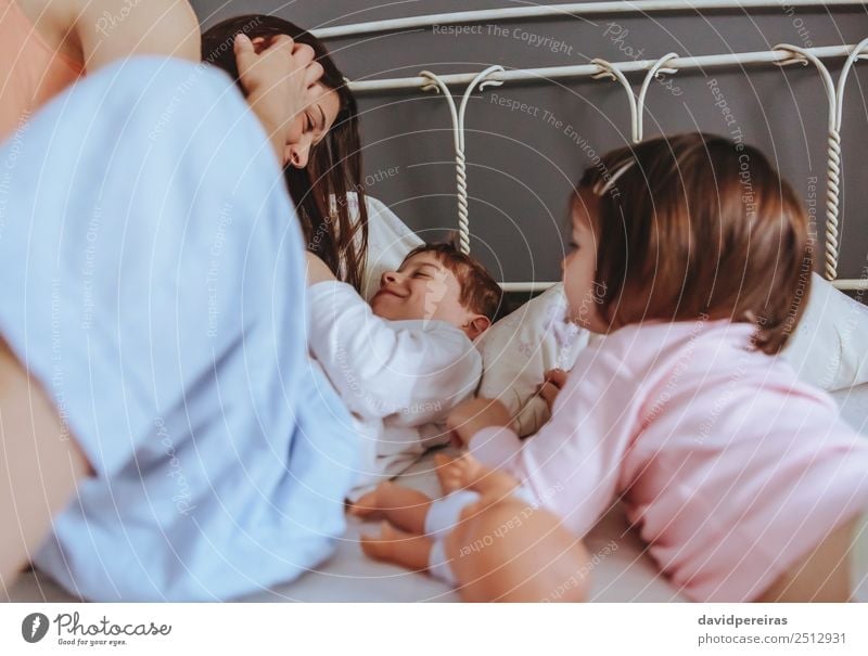Relaxed mother and sons playing over the bed Lifestyle Joy Happy Beautiful Relaxation Leisure and hobbies Playing Bedroom Child Baby Boy (child) Woman Adults