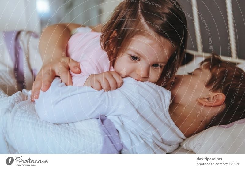 Little girl playing over boy lying in the bed Lifestyle Joy Happy Relaxation Leisure and hobbies Playing Bedroom Child Baby Boy (child) Woman Adults Parents