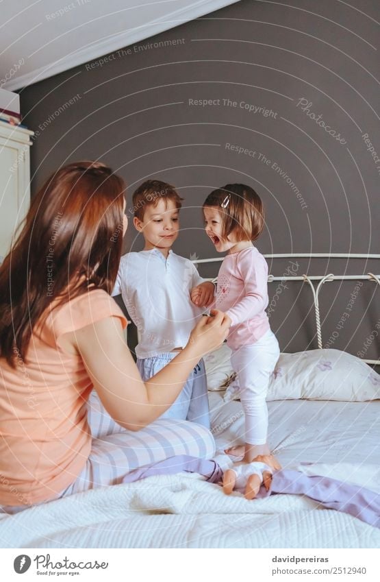 Relaxed mother and sons playing over the bed Lifestyle Joy Happy Beautiful Relaxation Leisure and hobbies Playing Bedroom Child Baby Boy (child) Woman Adults