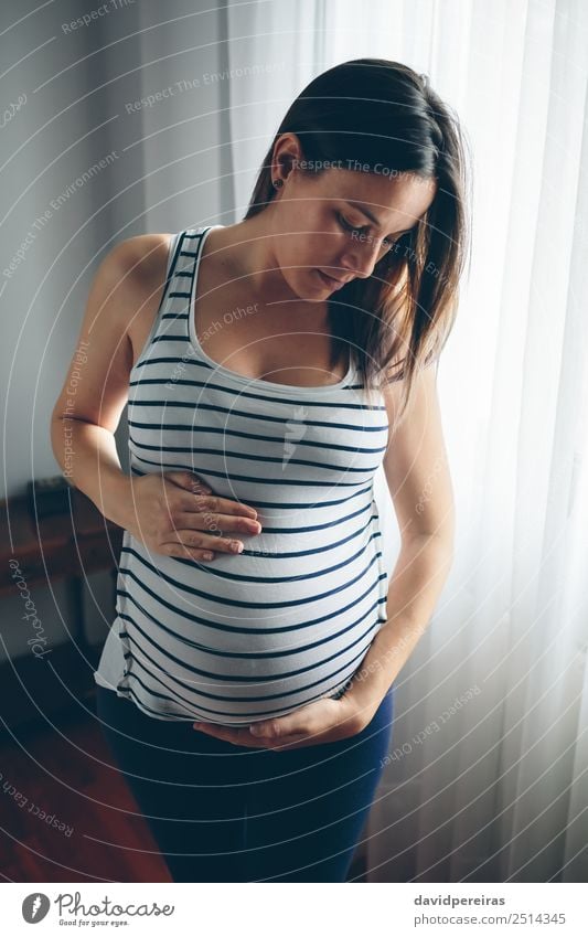 Pregnant woman looking her belly Lifestyle Beautiful Calm Parenting Human being Baby Woman Adults Parents Mother Hand Think Love Wait Authentic Serene
