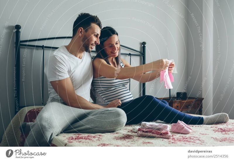 Man and pregnant woman looking baby clothes Happy Beautiful Bedroom Hospital Human being Baby Woman Adults Mother Father Family & Relations Couple Partner