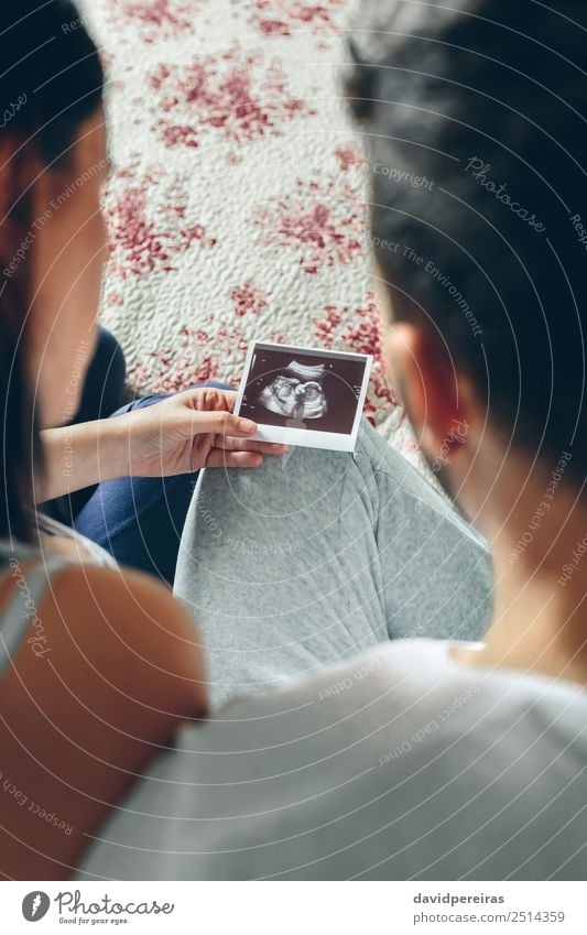 Couple looking baby ultrasound sitting on bed Examinations and Tests Human being Baby Woman Adults Man Parents Mother Father Family & Relations Partner Aircraft