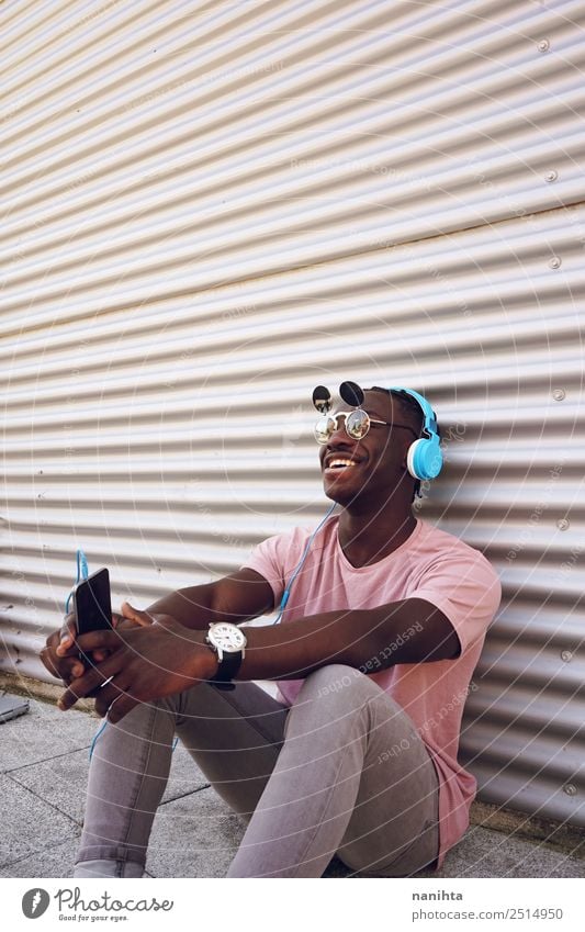 Young happy man listening to music Lifestyle Elegant Style Joy Leisure and hobbies Cellphone Headset Headphones Technology Entertainment electronics Human being