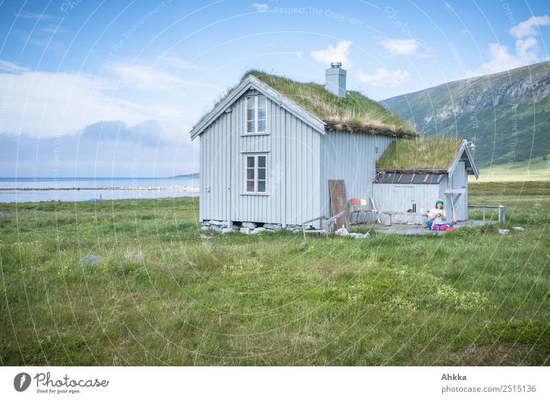 Idyllic wooden cabin by the fjord with overgrown roof in good weather and with young knitting woman in Norway Harmonious Well-being Contentment Relaxation Calm