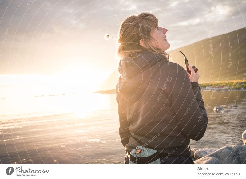 Young woman with pipe backlit by the sea in the midnight sun Midnight sun Freedom Sunlight Pipe Joie de vivre (Vitality) Contentment