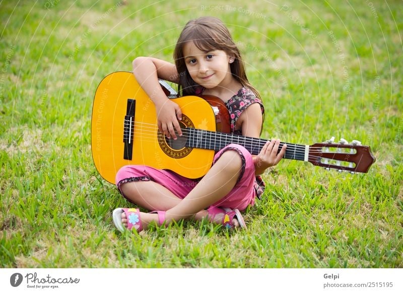 Girl with a guitar in the green grass Music Child School Human being Boy (child) Guitar Musical notes Flower Grass Green Pink girl student spanish handsome