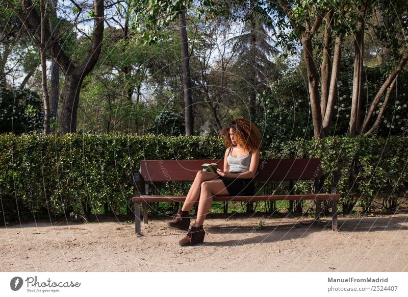 afro woman reading a book on a bench Lifestyle Happy Beautiful Leisure and hobbies Reading Summer School Study Human being Woman Adults Book Nature Tree Grass