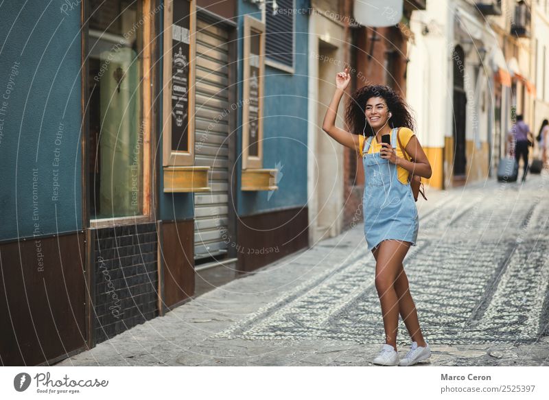 beautiful mixed girl listening to the music walking happy in the street - a  Royalty Free Stock Photo from Photocase