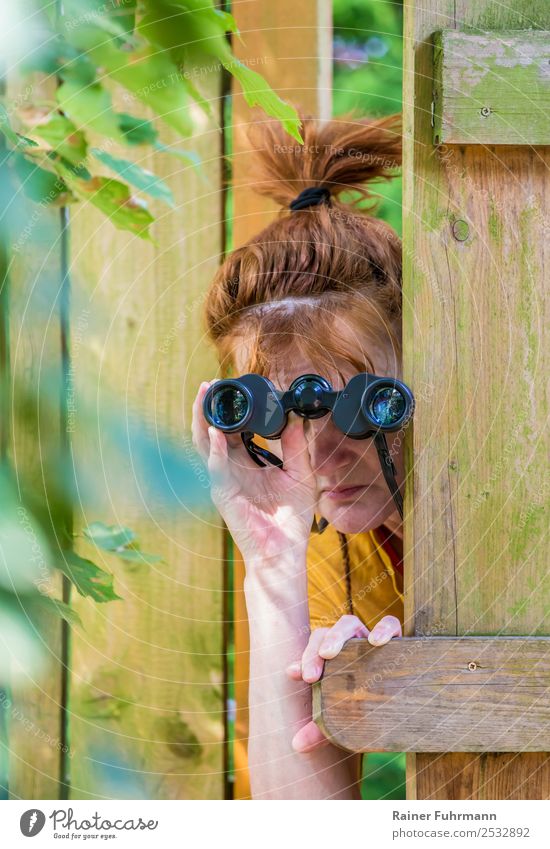 a curious woman observes with binoculars Human being Feminine Woman Adults Head 1 Environment Garden Fence Observe Curiosity Watchfulness Envy "Binoculars