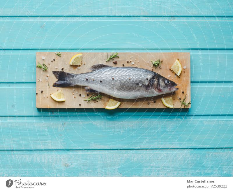 Sea bass on kitchen table with lemon and rosemary Seafood Herbs and spices Eating Dinner Diet Table Restaurant Animal Wood Write Fresh Delicious Blue