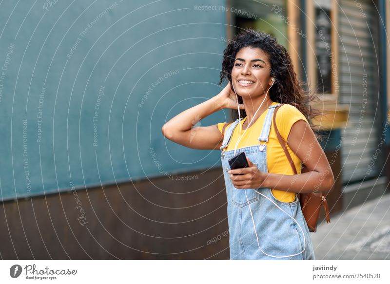 African woman listening to music with earphones Feminine Young woman Youth (Young adults) Woman Adults 1 Human being 18 - 30 years Movement Smiling Walking