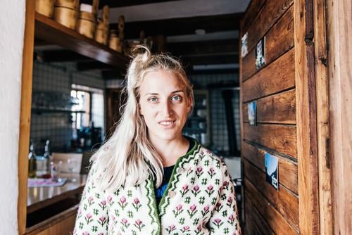 Young woman in alpine hut Style Feminine Youth (Young adults) 18 - 30 years Adults Hut Costume Cardigan Blonde Long-haired Work and employment Smiling Laughter